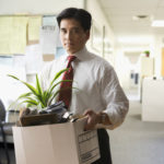Fired Chinese businessman carrying box of personal items
