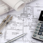 Ein Bauplan eines Architekten mit einem Taschenrechner. Symbolfoto für Finanzierung und Planung eines neuen Hauses.